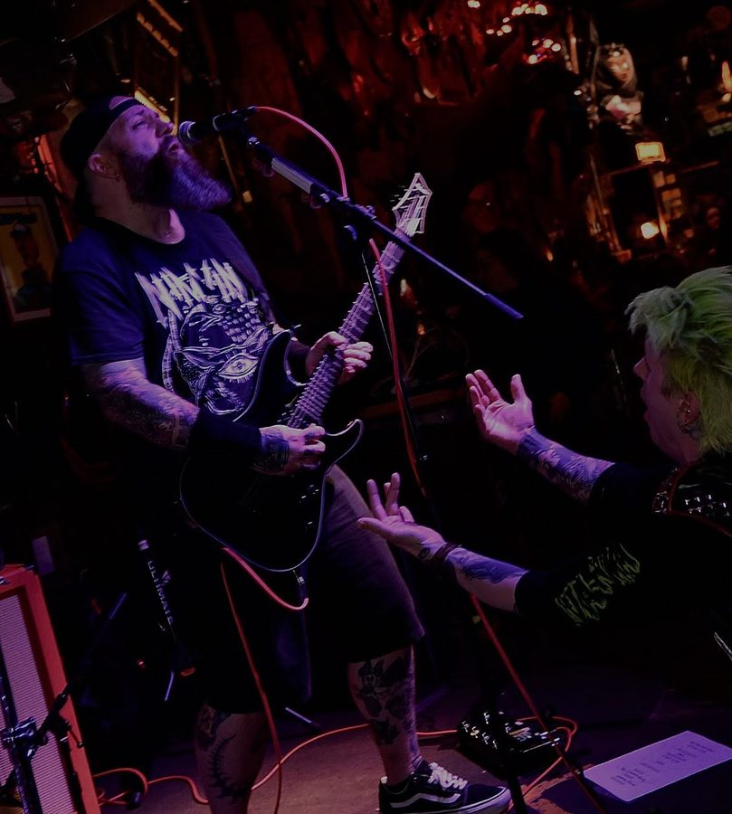 Nate Laff singing and playing guitar as a fan reaches toward the stage